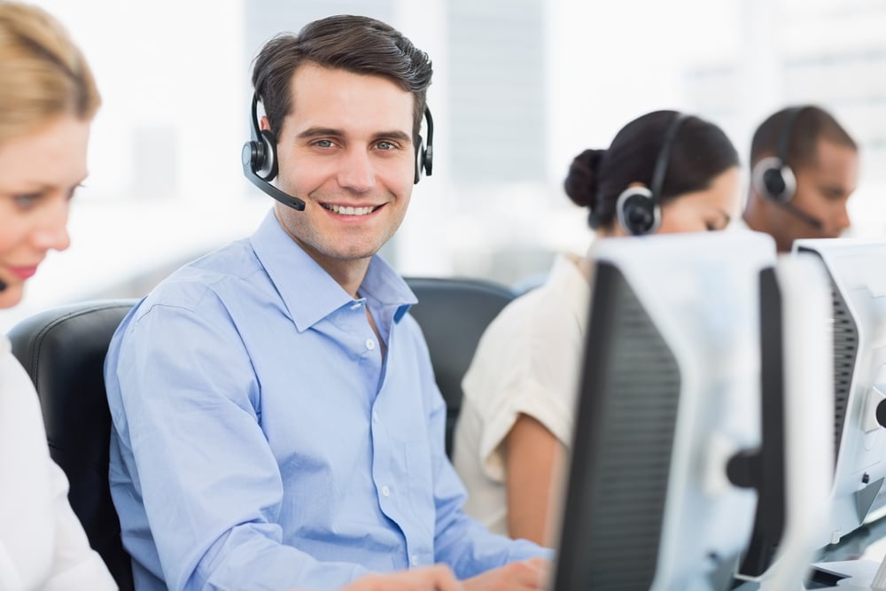 Side view portrait of business colleagues with headsets using computers at office